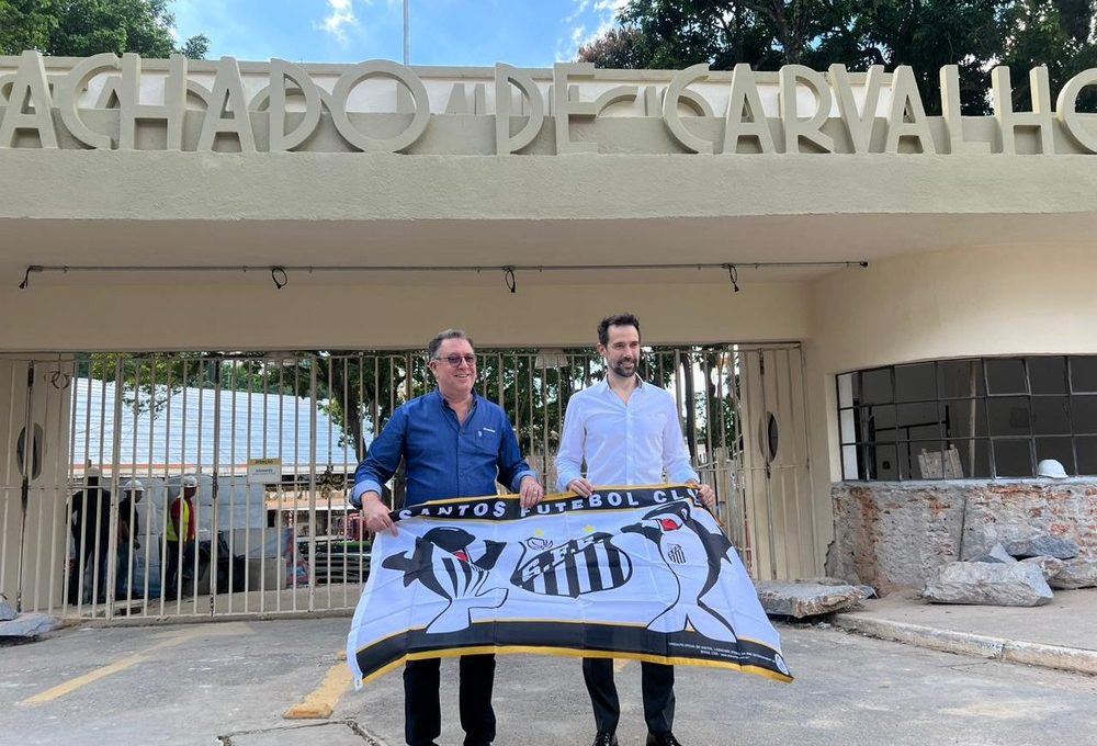 Marcelo Teixeira, presidente eleito do Santos, e Eduardo Barella, CEO da concessionária Allegra Pacaembu, posam com bandeira do Peixe na frente do estádio — Foto: Divulgação